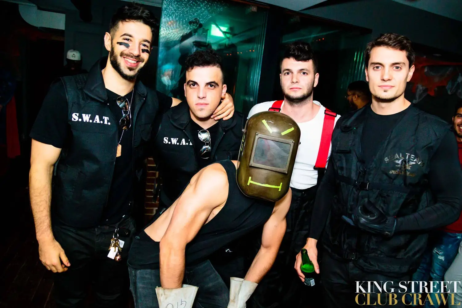 A group of friends in SWAT and welder Halloween costumes at a club crawl